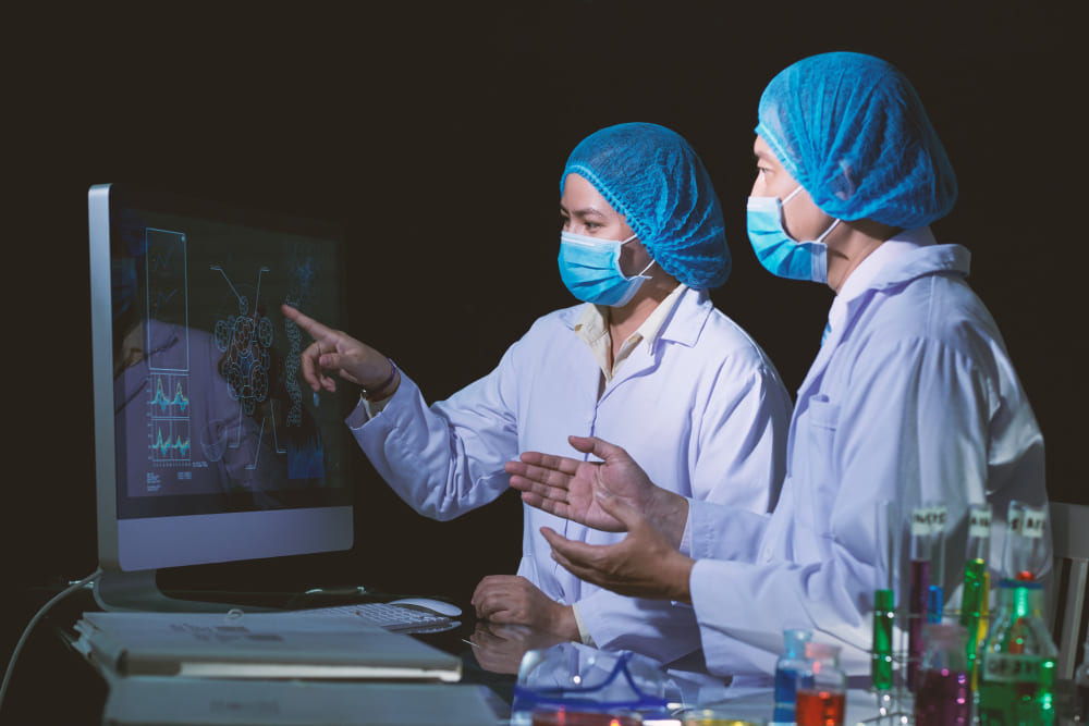 Deux scientifiques analysant sur écran des données techniques issues d’une veille de recherche