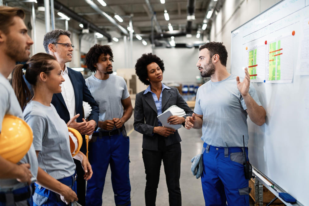 Équipe industrielle analysant un tableau de suivi dans le cadre d’une étude de faisabilité